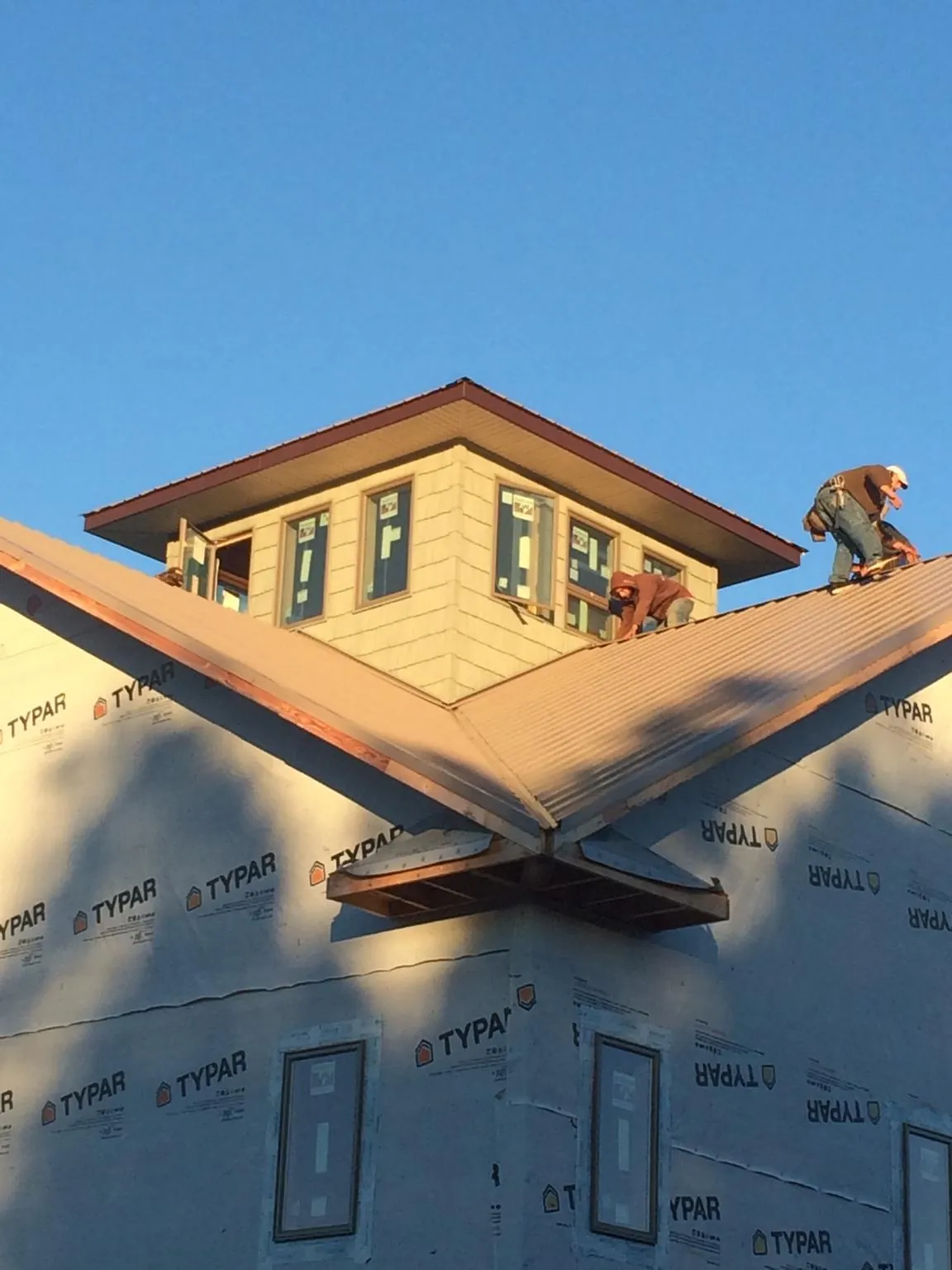 Roofers working around a rooftop cupola on a new metal roof at sunset — Roof Waterproofing in Rockville by Roofing Brothers